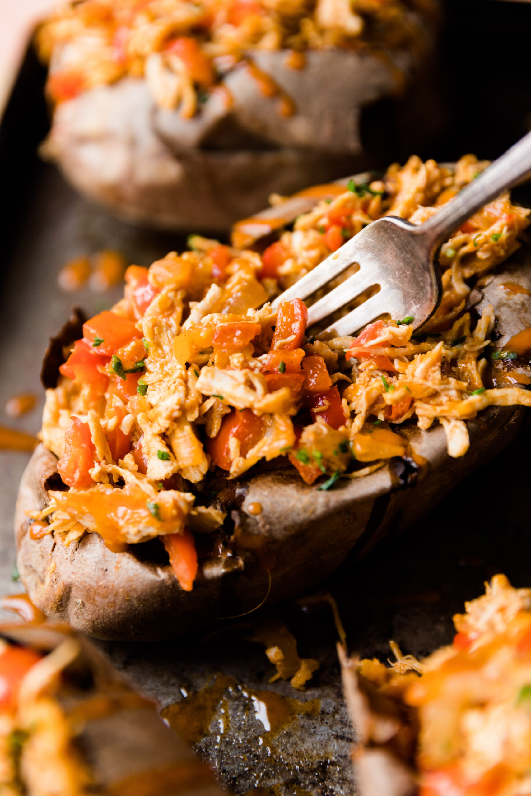 Fork scooping out buffalo chicken stuffed sweet potato.