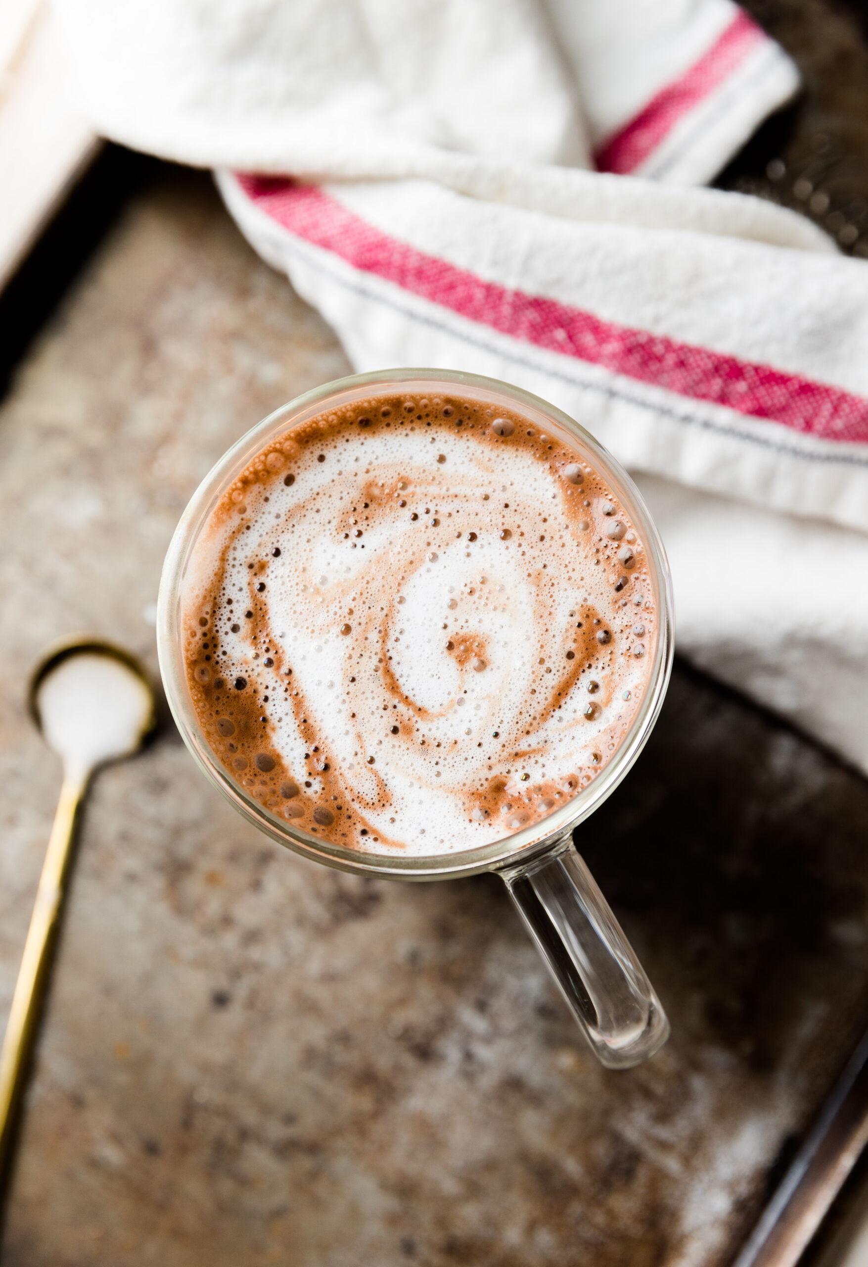 Overhead picture of creamy hot chocolate in glass mug.
