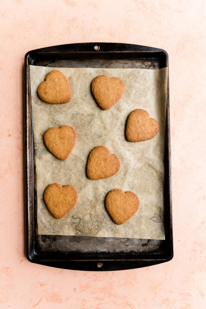Baked cut out sugar cookies on parchment paper lined baking sheet.