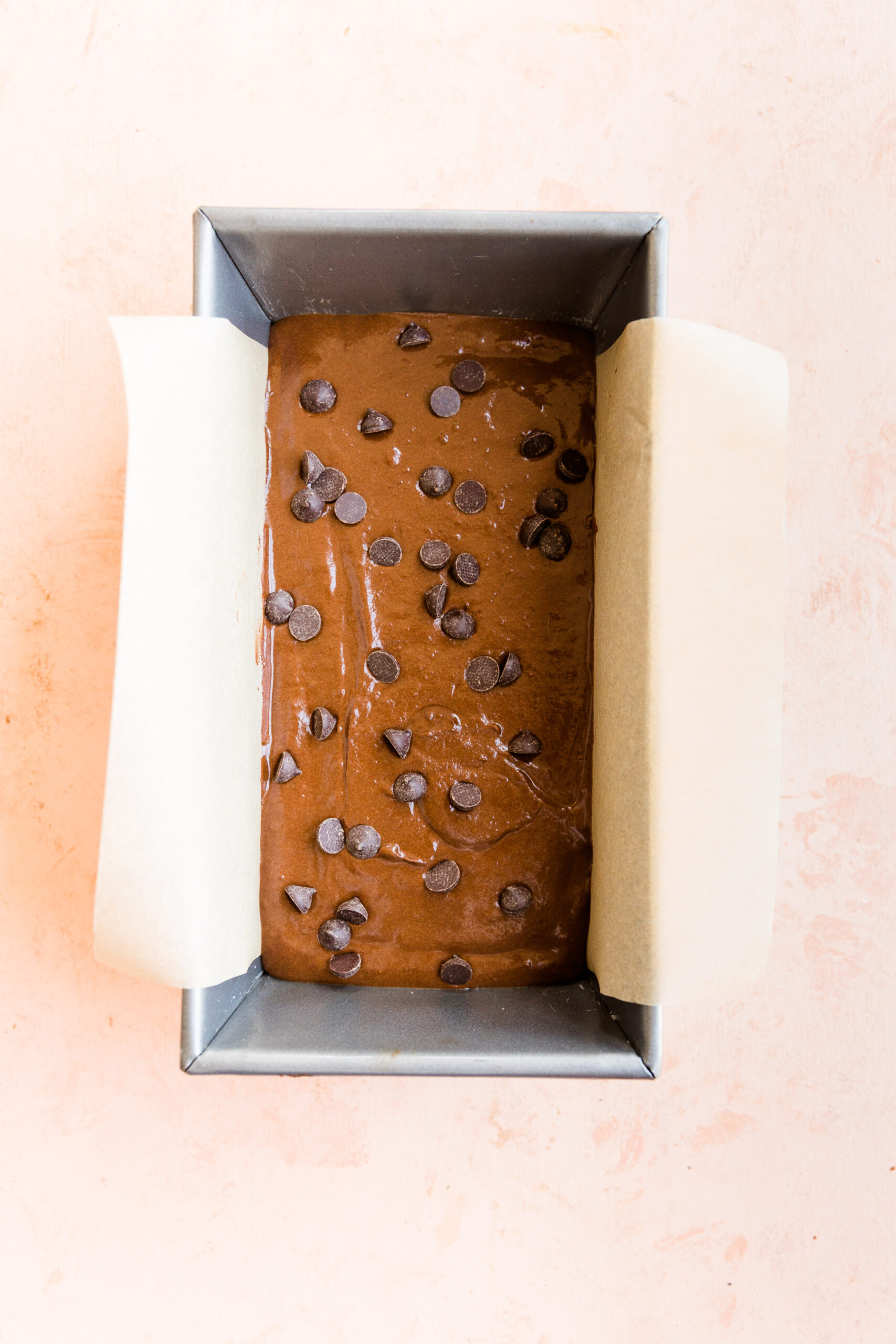 Brownie batter with chocolate chips on top in baking pan.