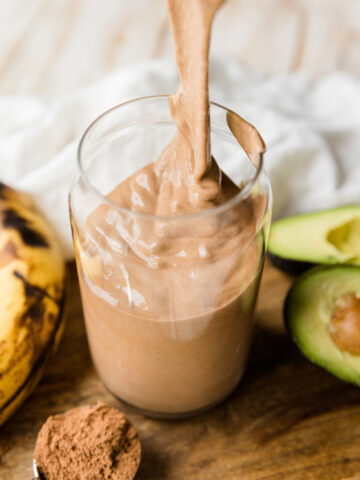 Thick chocolate protein shake being poured into glass cup.