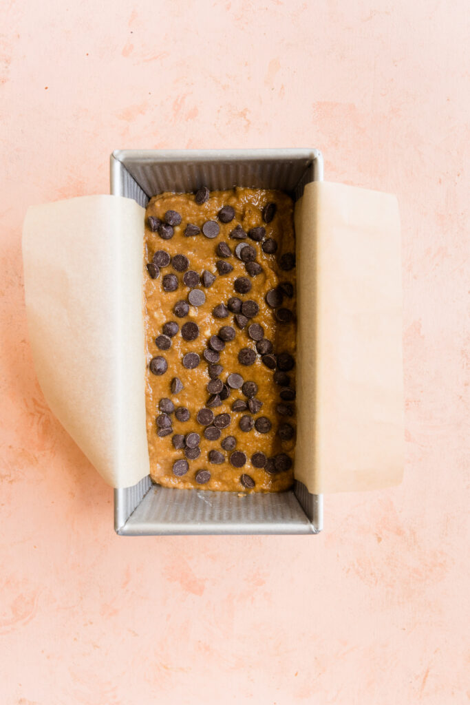 Banana bread batter with chocolate chips in a loaf pan.