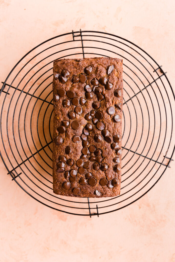 Banana bread with chocolate chips cooling on a metal rack.