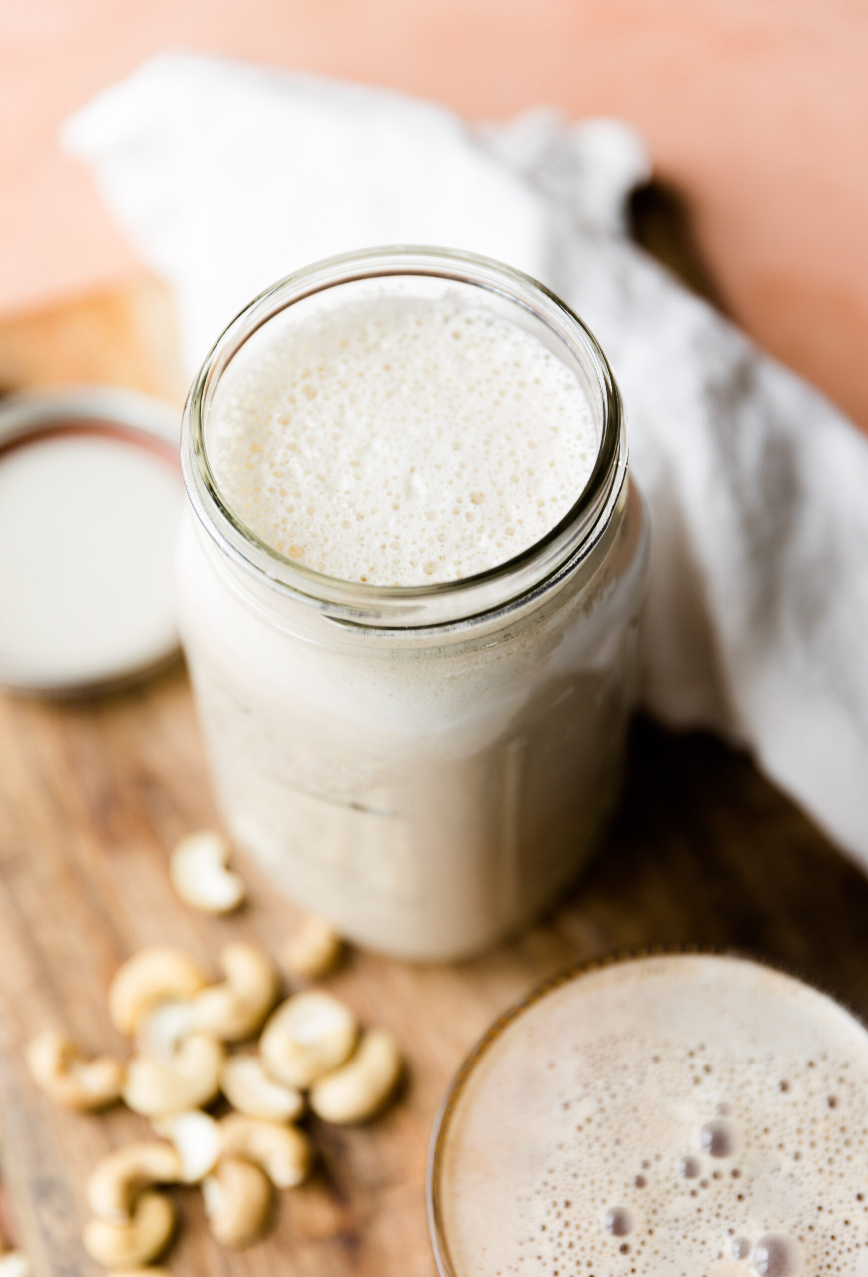 Cashew coffee creamer in a glass mason jar with raw cashews on the side.