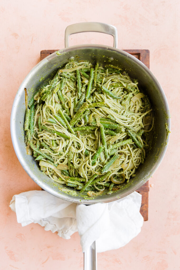 Cooked vegetables mixed with gluten free spaghetti in large pan.