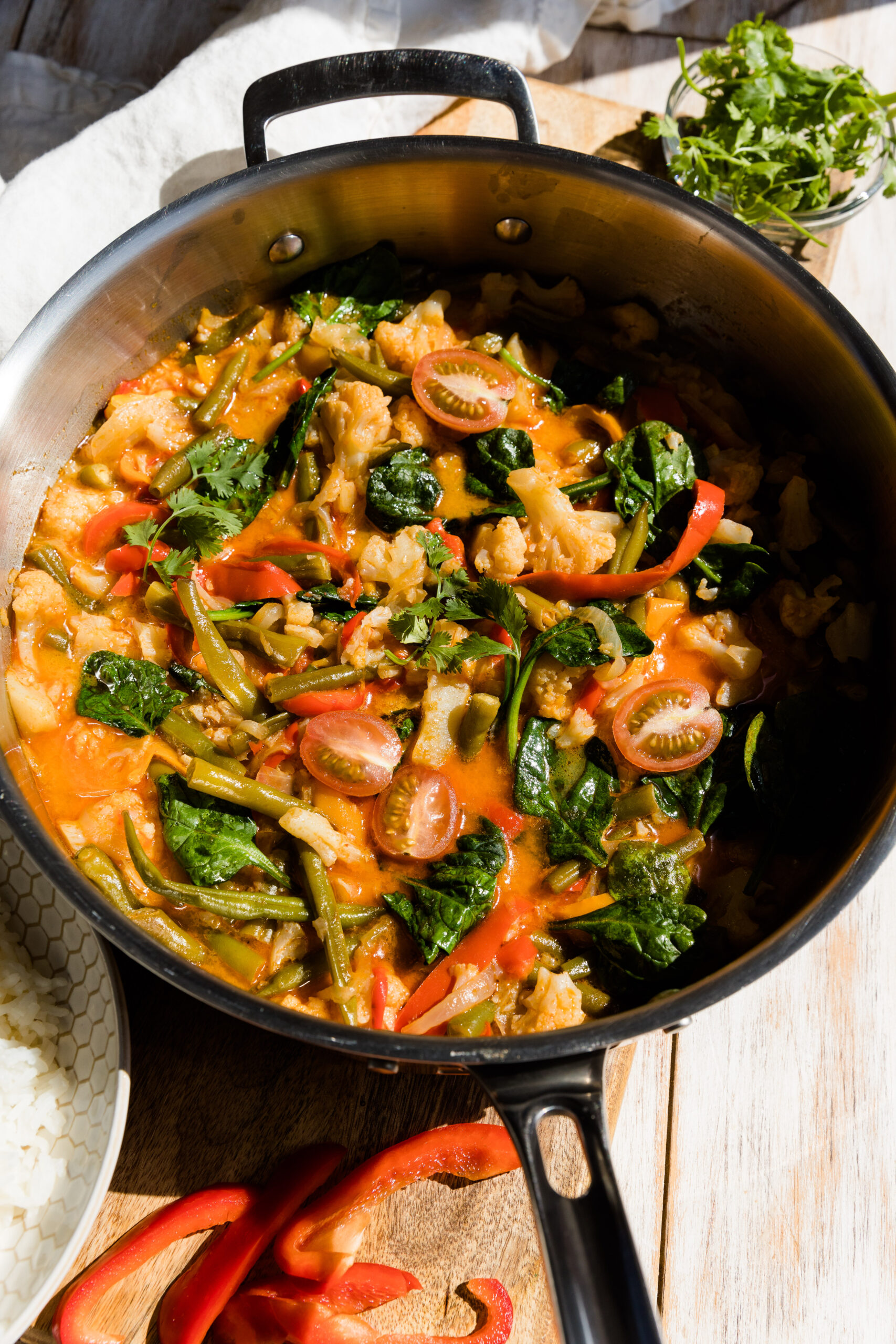 Large saute pan filled with red curry and vegetables.