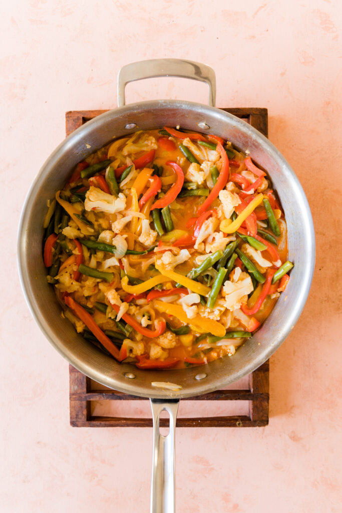 Cooked vegetables in red curry sauce.