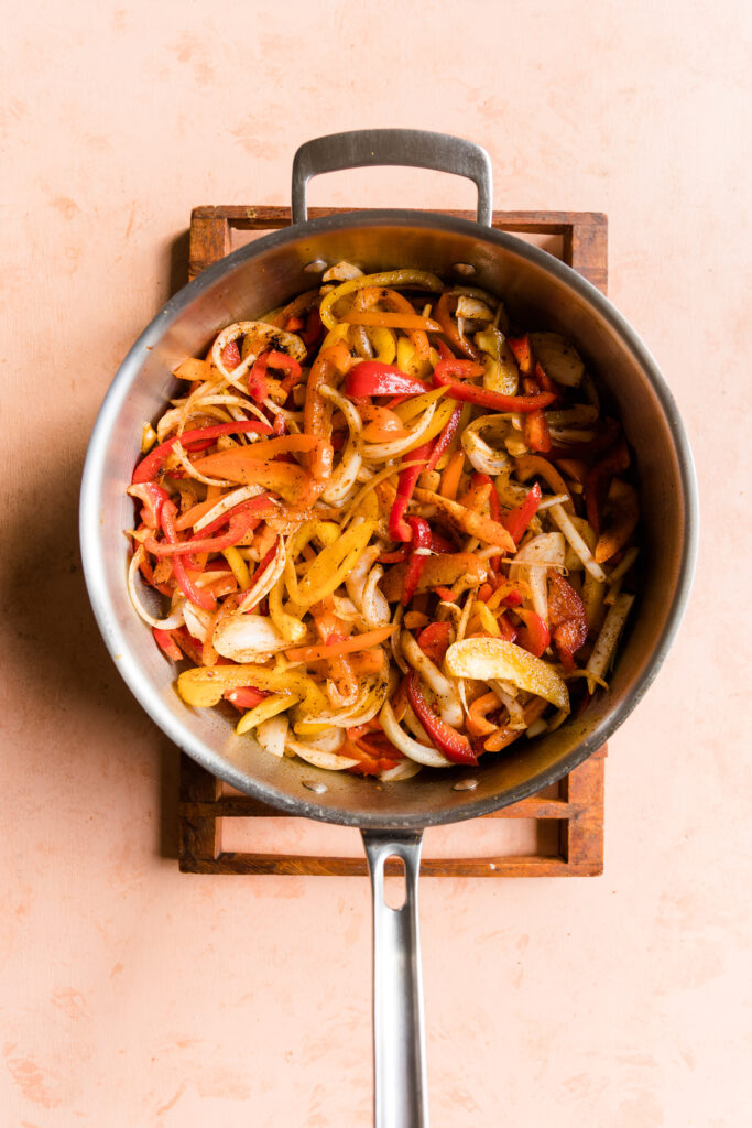 Fajita style peppers and onions in a large pan.