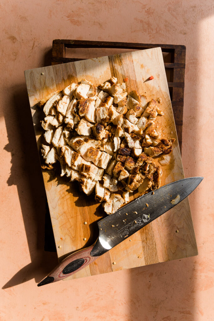 Cooked fajita chicken chopped on cutting board.