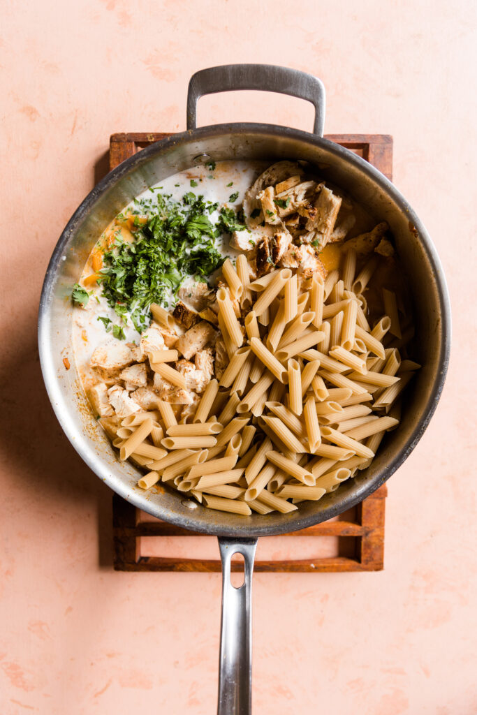 Pasta, cilantro, chicken, peppers, and onions in pan.