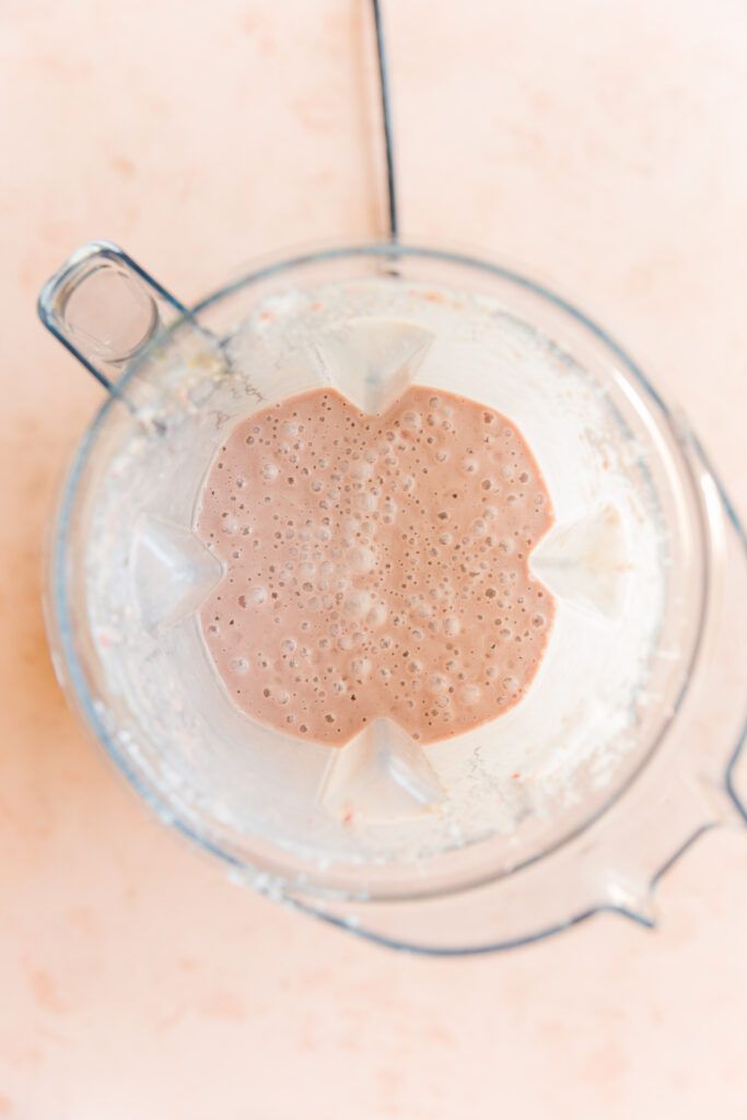 Creamy strawberry ice cream in blender.
