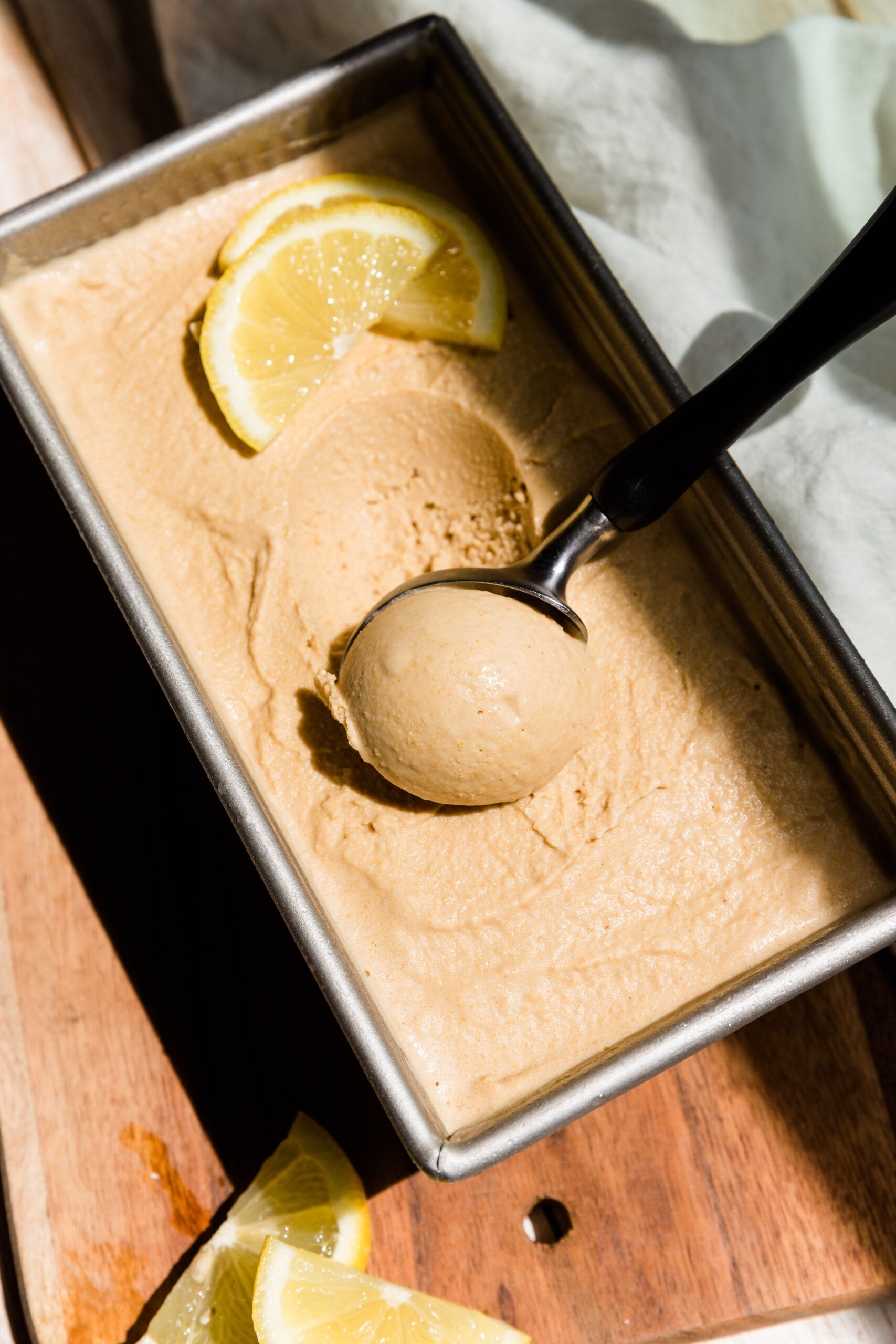Scooping out ball of lemon ice cream with an ice cream scooper.