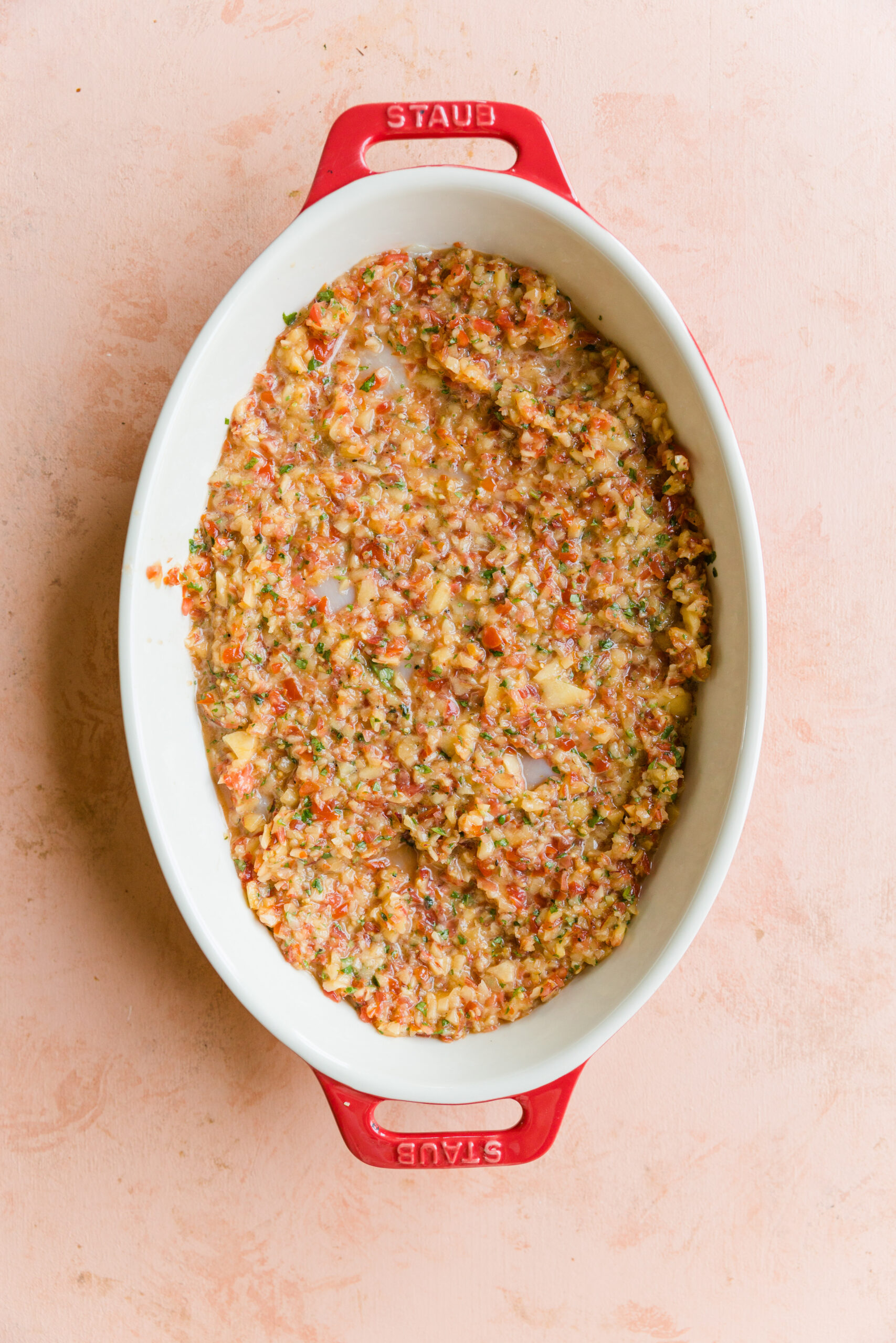 Peach salsa covering uncooked chicken breast in a casserole dish.