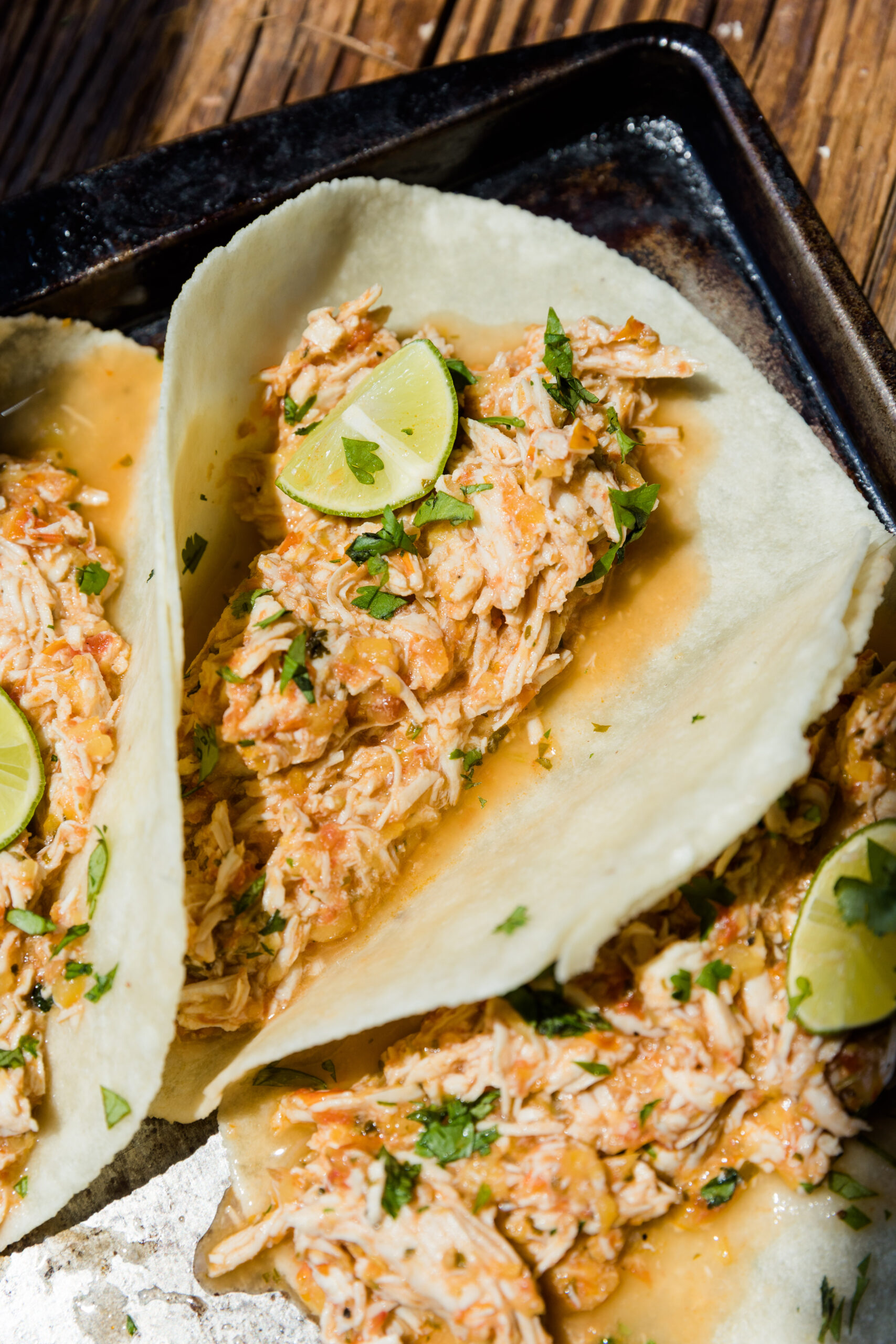 Peach salsa chicken tacos with lime wedges and fresh cilantro sprinkled on top.