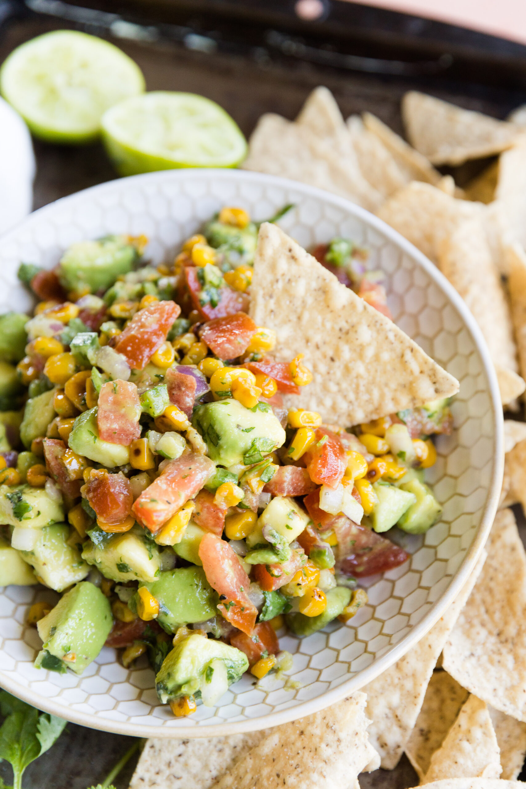Chip scooping out avocado corn salsa recipe.