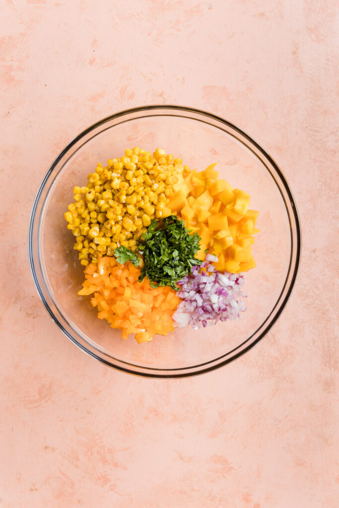 Ingredients in mixing bowl for mango corn salsa.