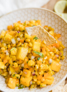 Chip scooping up mango corn salsa.