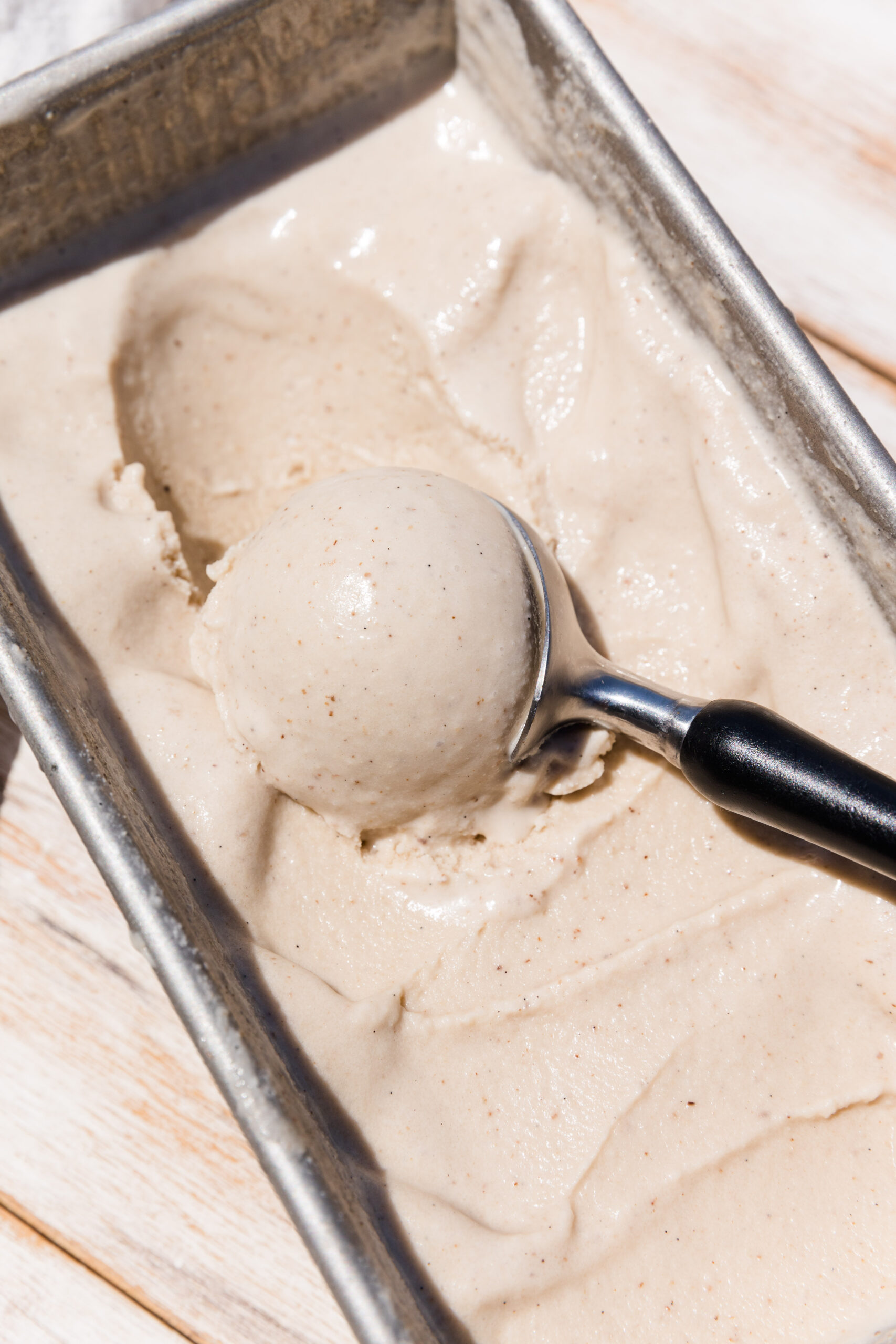 Ice cream scooper scooping out vanilla ice cream.
