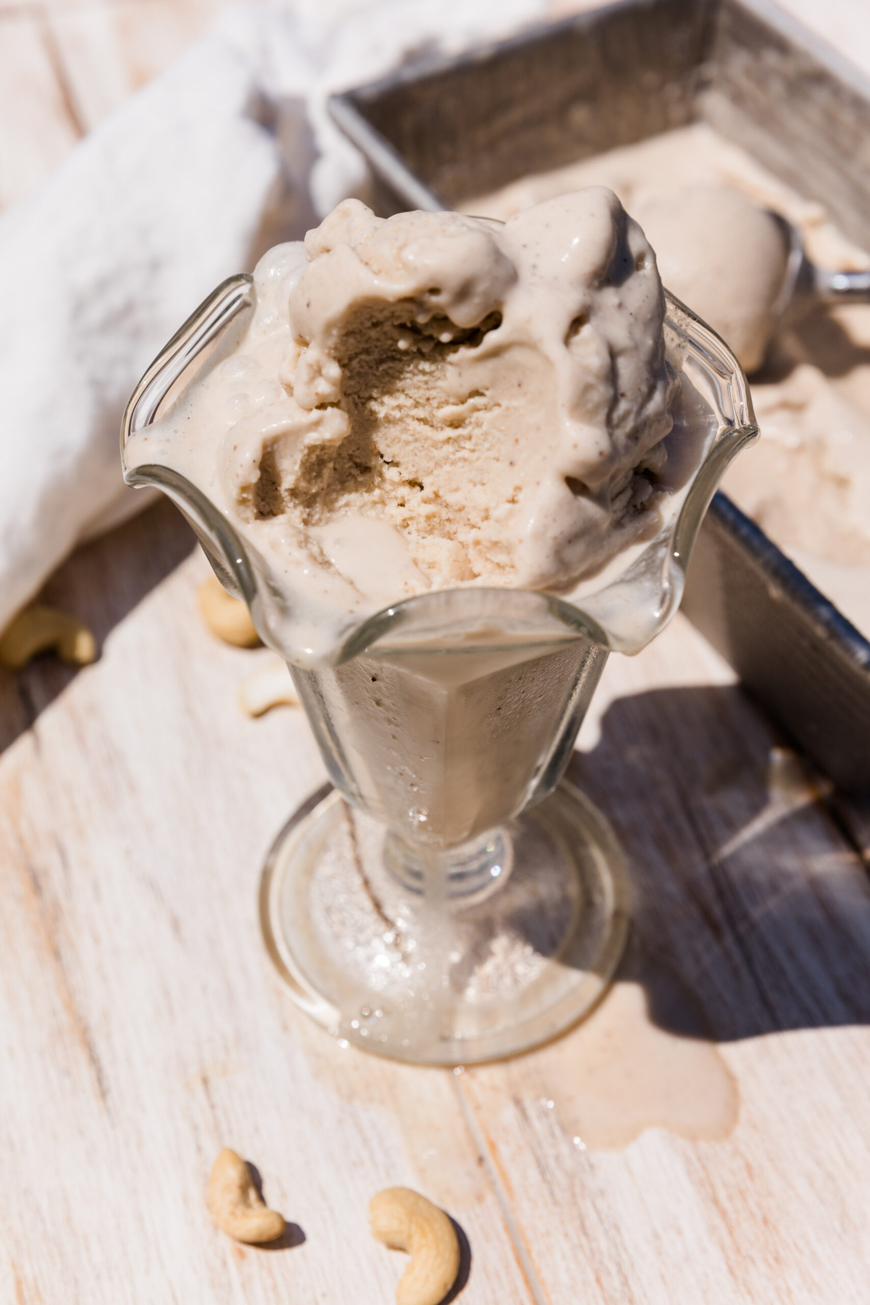 Vanilla ice cream in glass cup with a spoonful taken out.