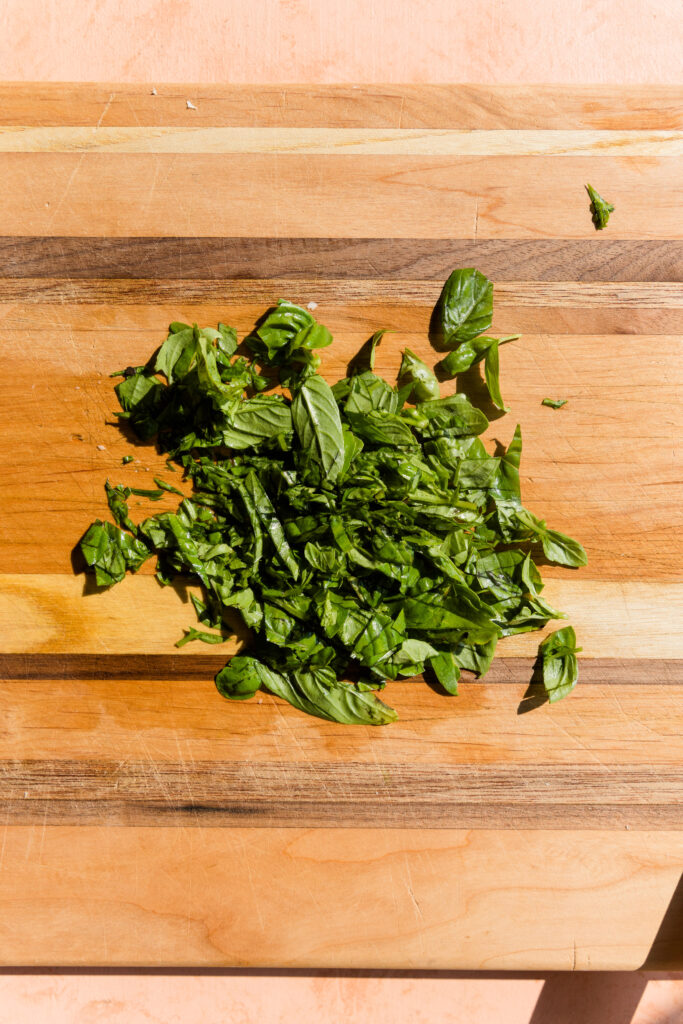 Fresh basil roughly chopped on cutting board.