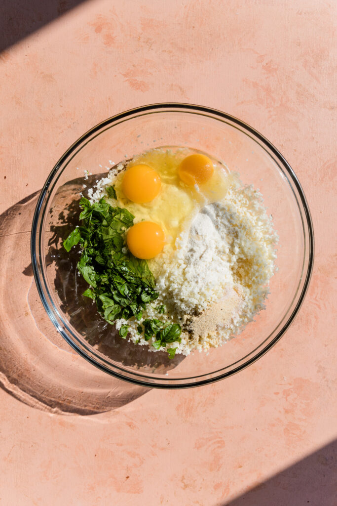 Ingredients in glass mixing bowl for cauliflower crust.
