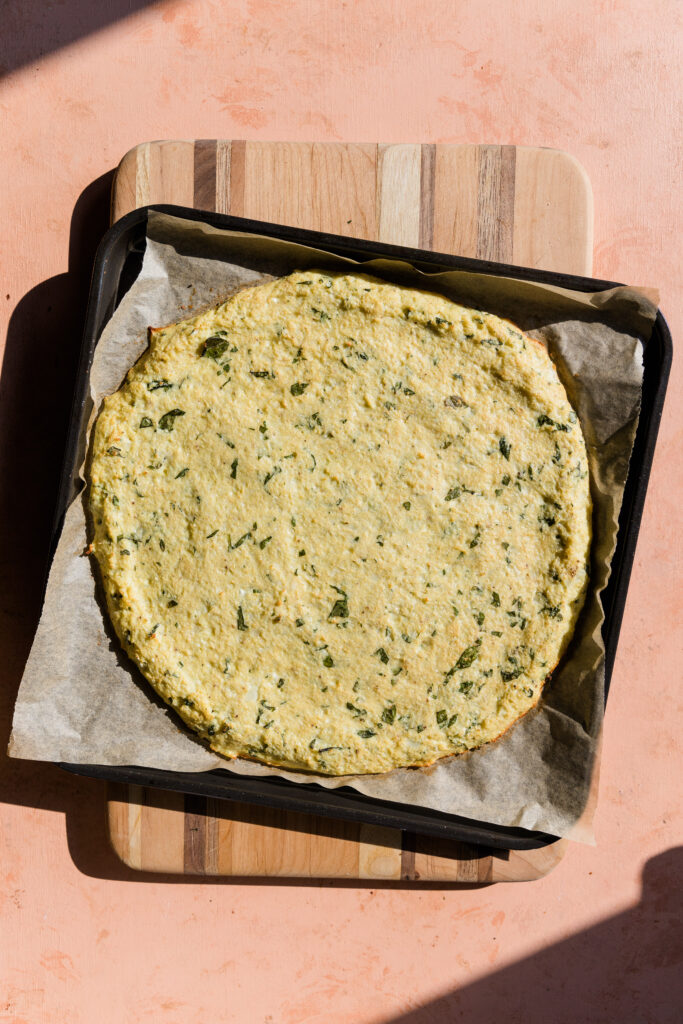 Golden brown cauliflower pizza crust on baking sheet.