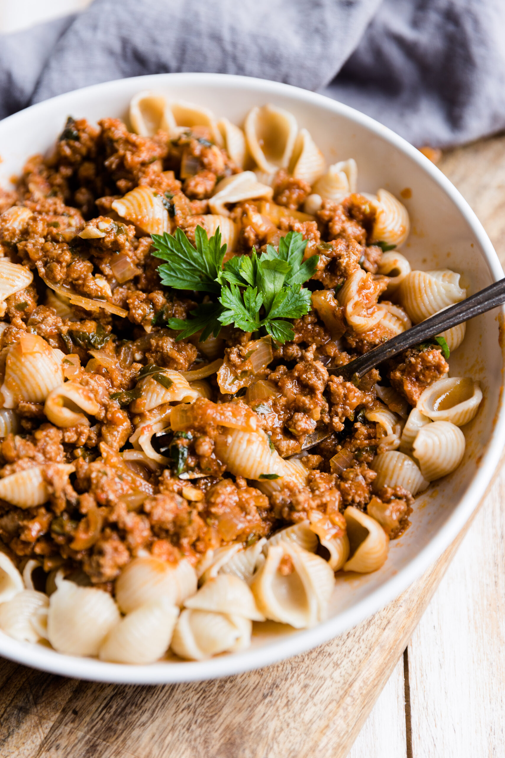 Fork scooping out meat sauce with pasta shells.