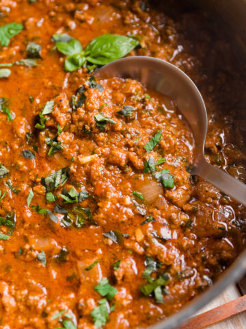 Ladle scooping out meat sauce from the pot.
