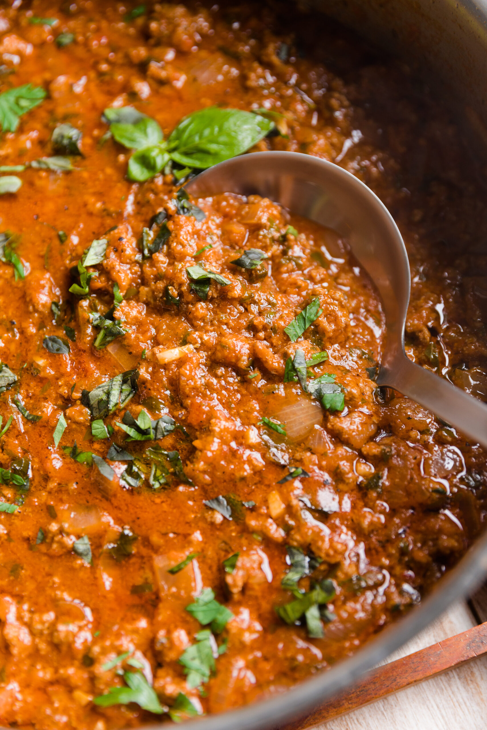 Ladle scooping out meat sauce from the pot.