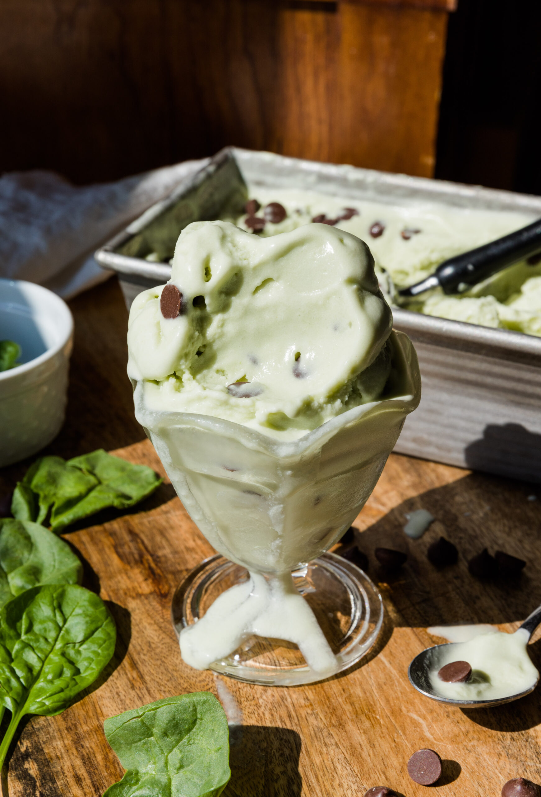 Mint chocolate chip ice cream in a glass cup with a spoonful taken out.