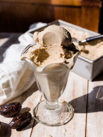 Salted caramel ice cream in a glass cup with a bite taken out.