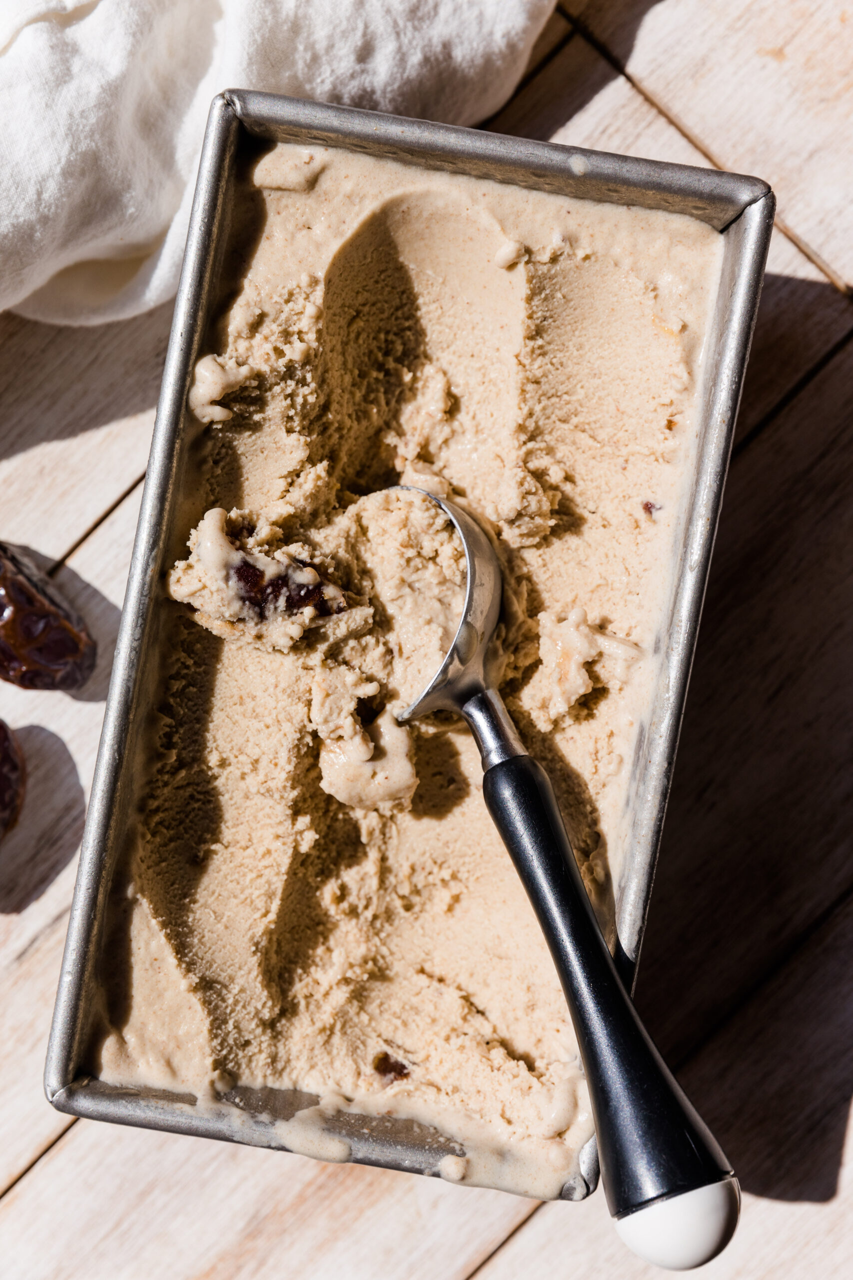 Salted caramel ice cream being scooped out of a metal loaf pan.