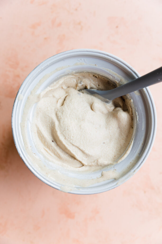 Creamy dairy free ice cream in ice cream maker with spatula.