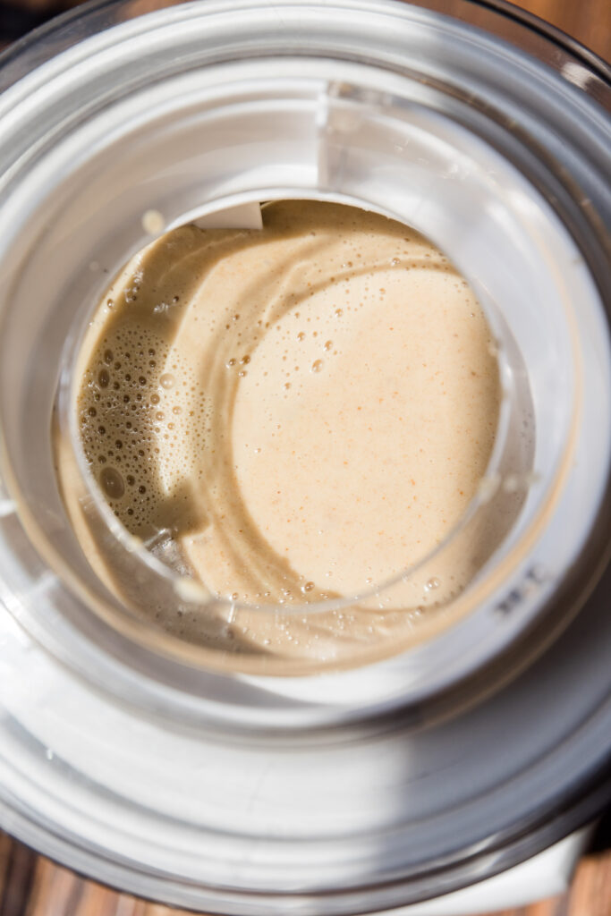 Liquid caramel ice cream mixture churning in ice cream maker.