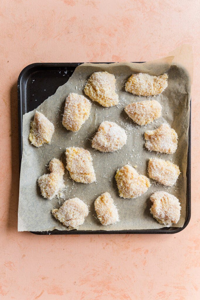 Chicken tenders on baking sheet coated in gluten-free flour mixture.