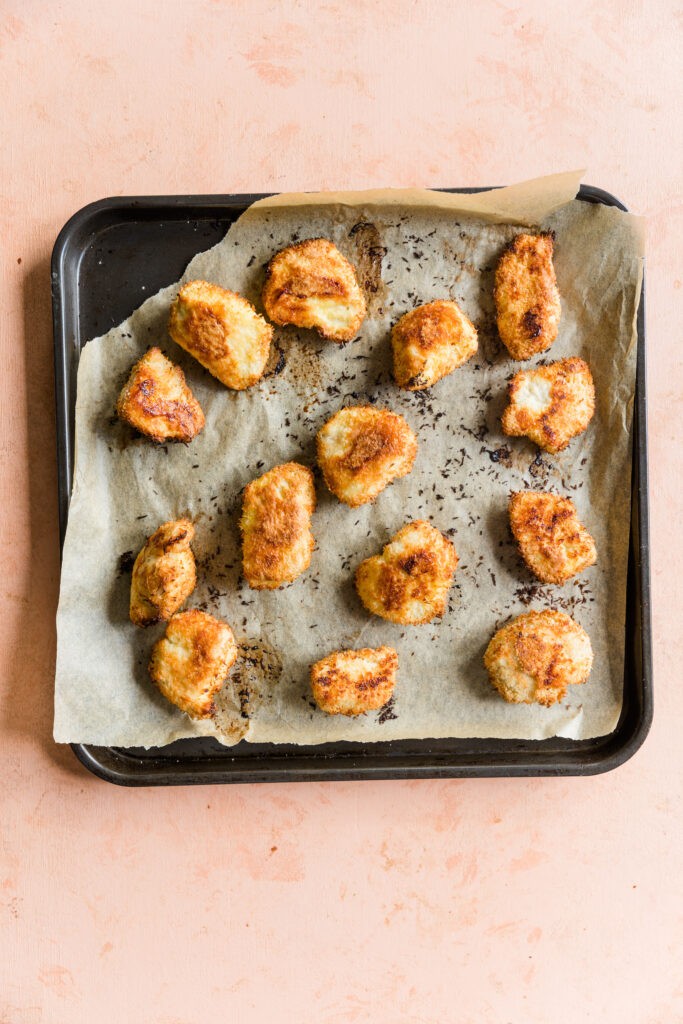 Crispy buffalo chicken tenders on baking sheet lined with parchment paper.