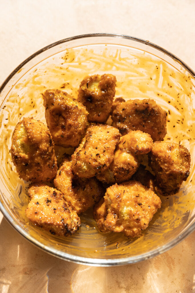 Crispy buffalo chicken tenders in glass bowl.