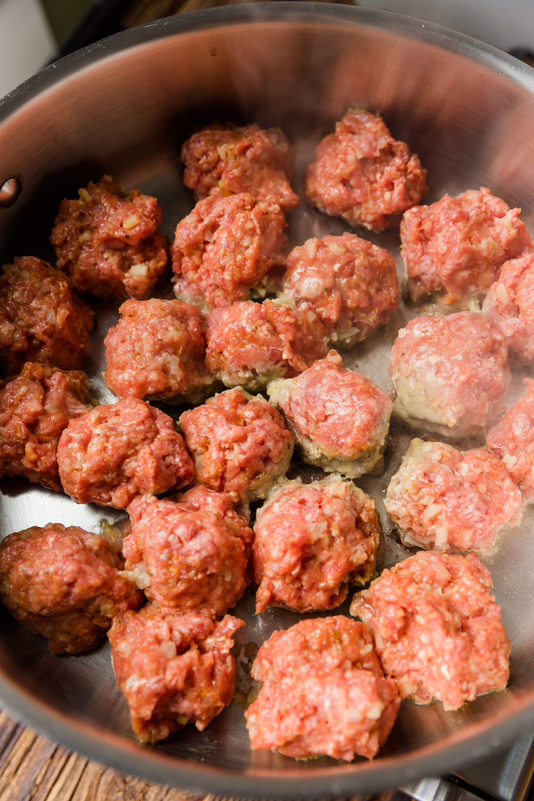 Meatballs cooking in large sauté pan.