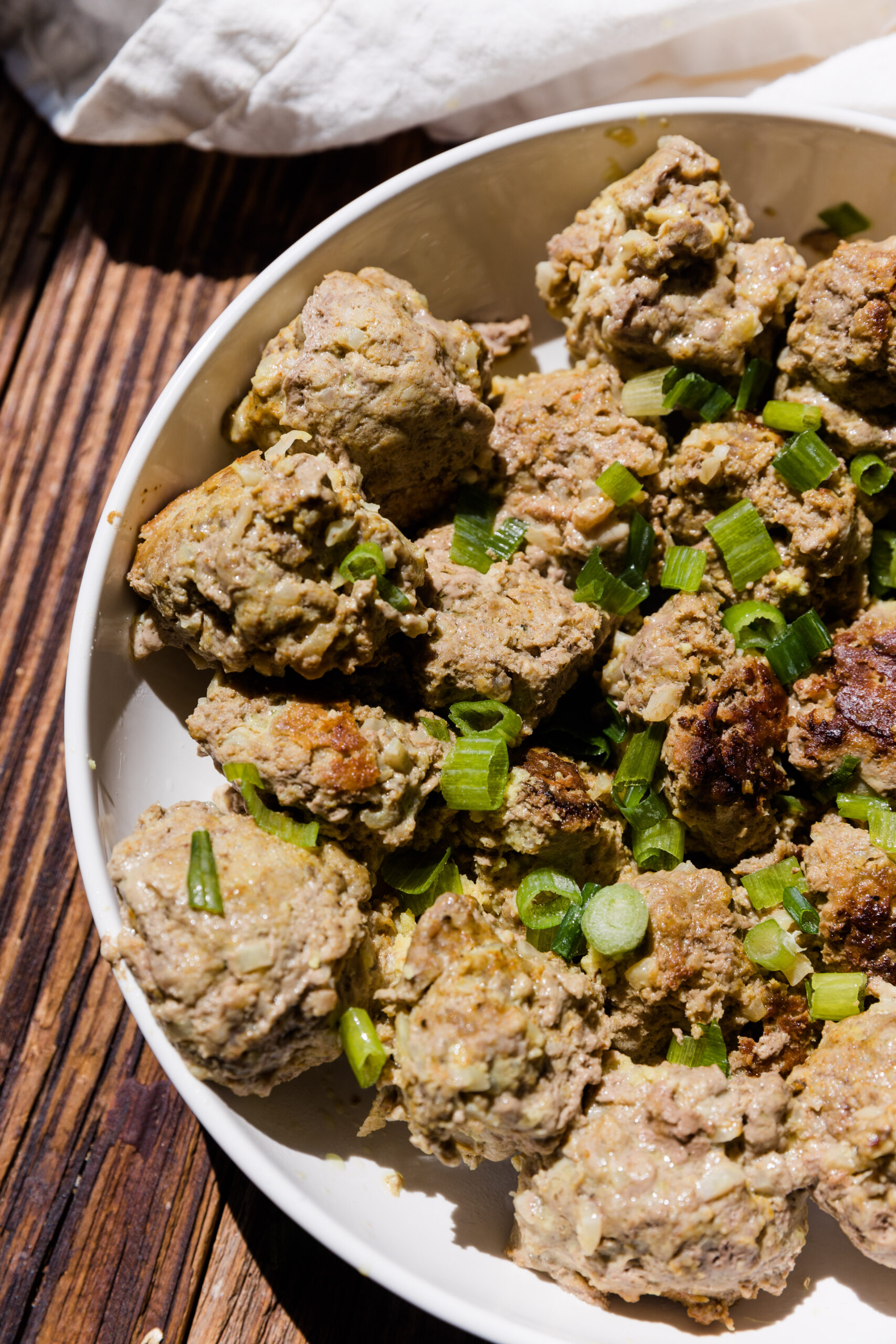 Golden brown ginger curry meatballs on a white plate.