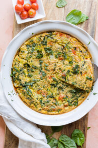 Overhead picture of frittata in a white ceramic baking dish cut into individual slices.