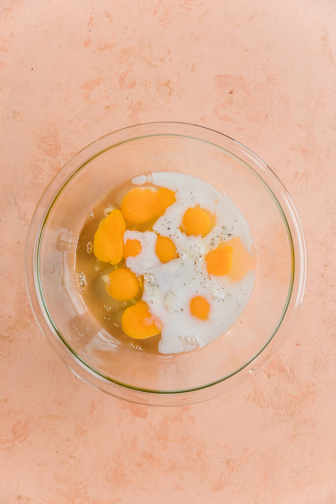 Eggs, coconut milk, and seasoning in a glass mixing bowl.