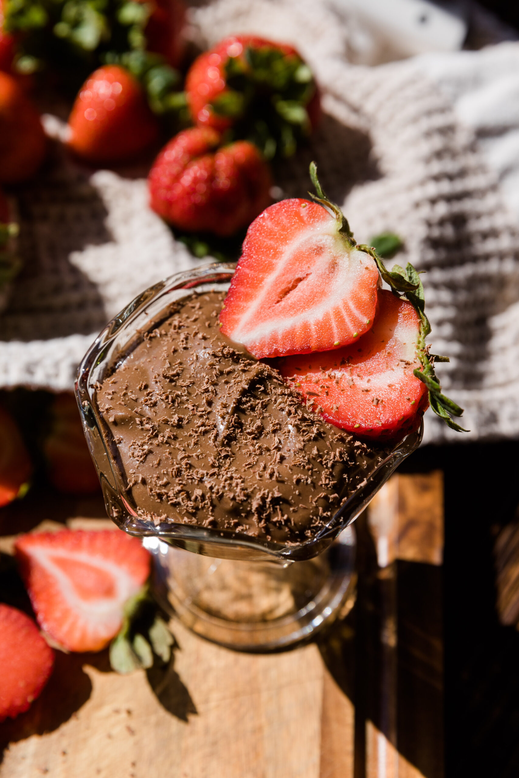 Avocado chocolate pudding in a glass jar with fresh cut strawberries on the side.