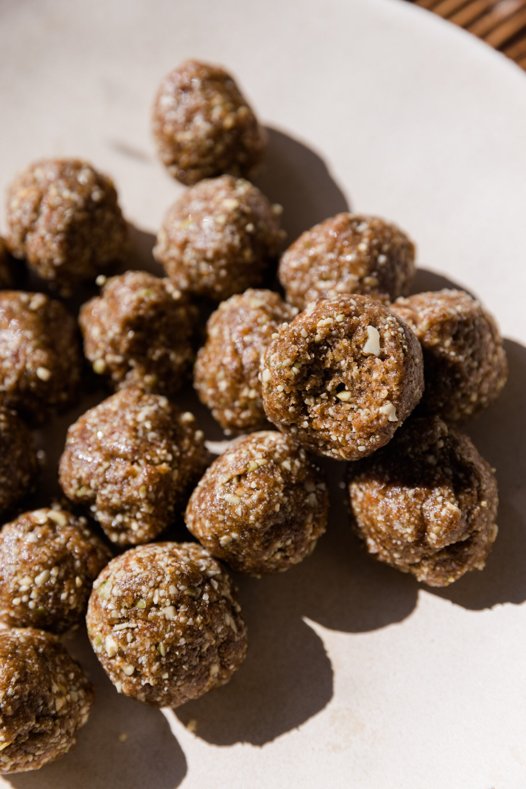 Cinnamon energy balls stacked on a ceramic plate.