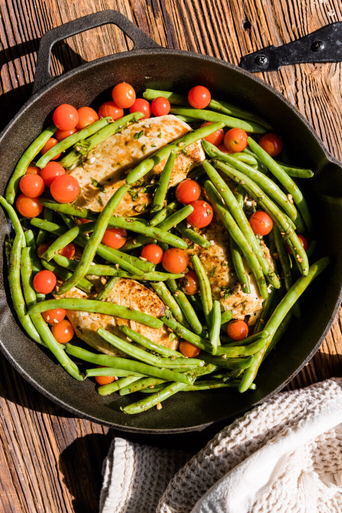 Chicken with tomatoes, green beans, and balsamic dressing in cast iron skillet.