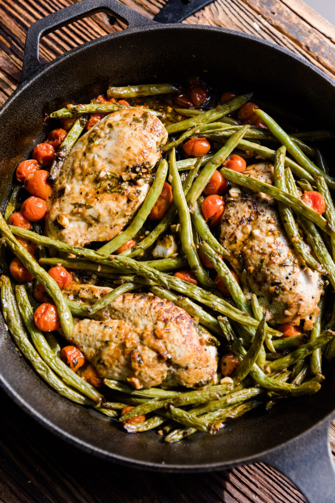 Baked chicken with vegetables in cast iron skillet.