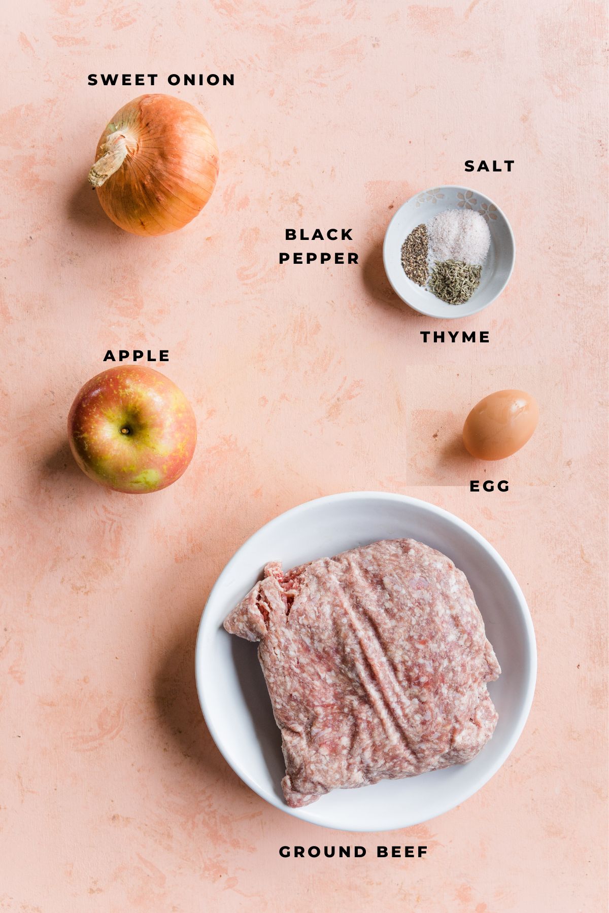 Apple herb meatball ingredients on a pink board.