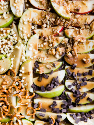Close up picture of caramel apples slices with a variety of toppings.