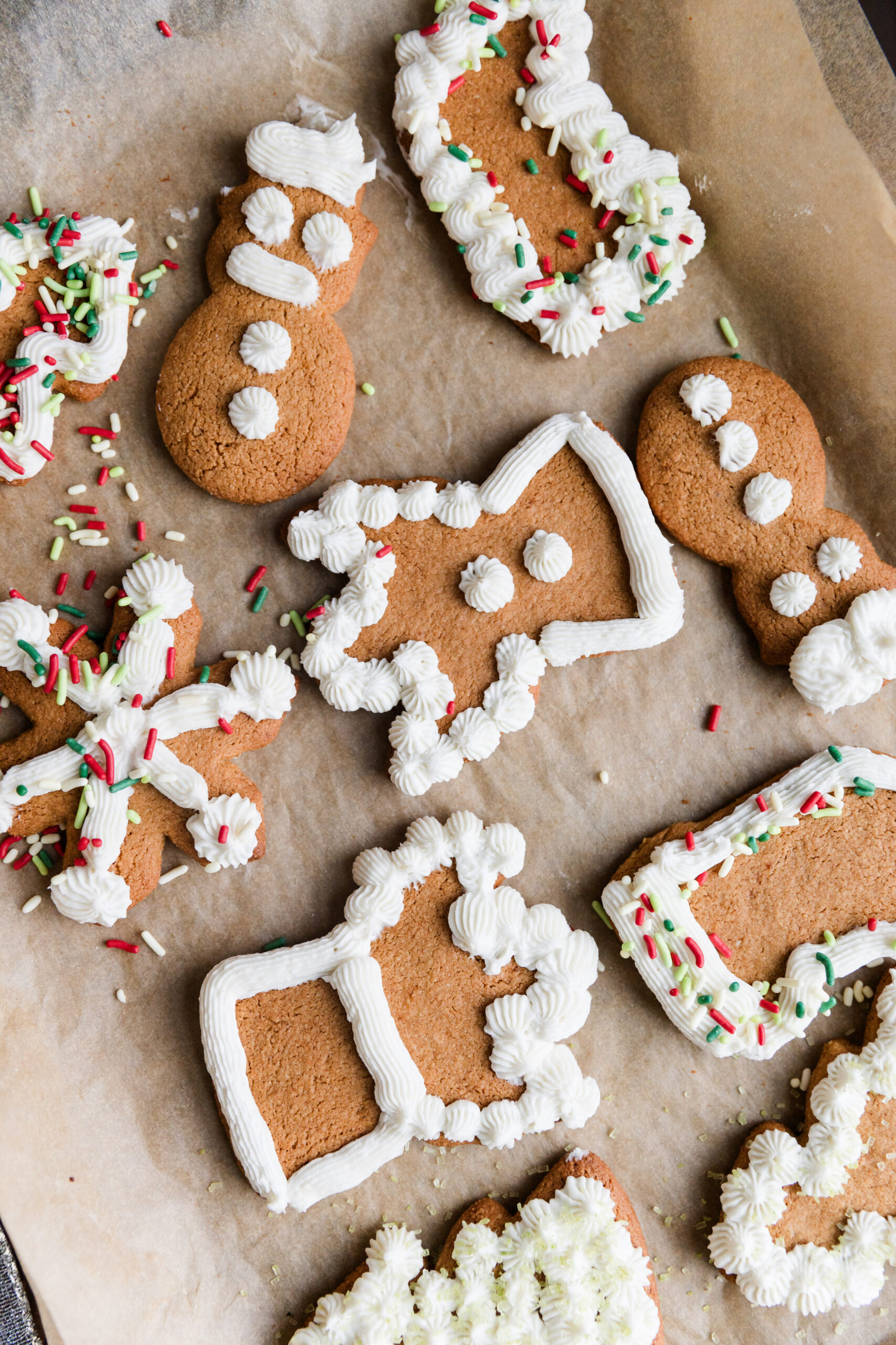 Variety of cut out cookies on baking sheet with white frosting.