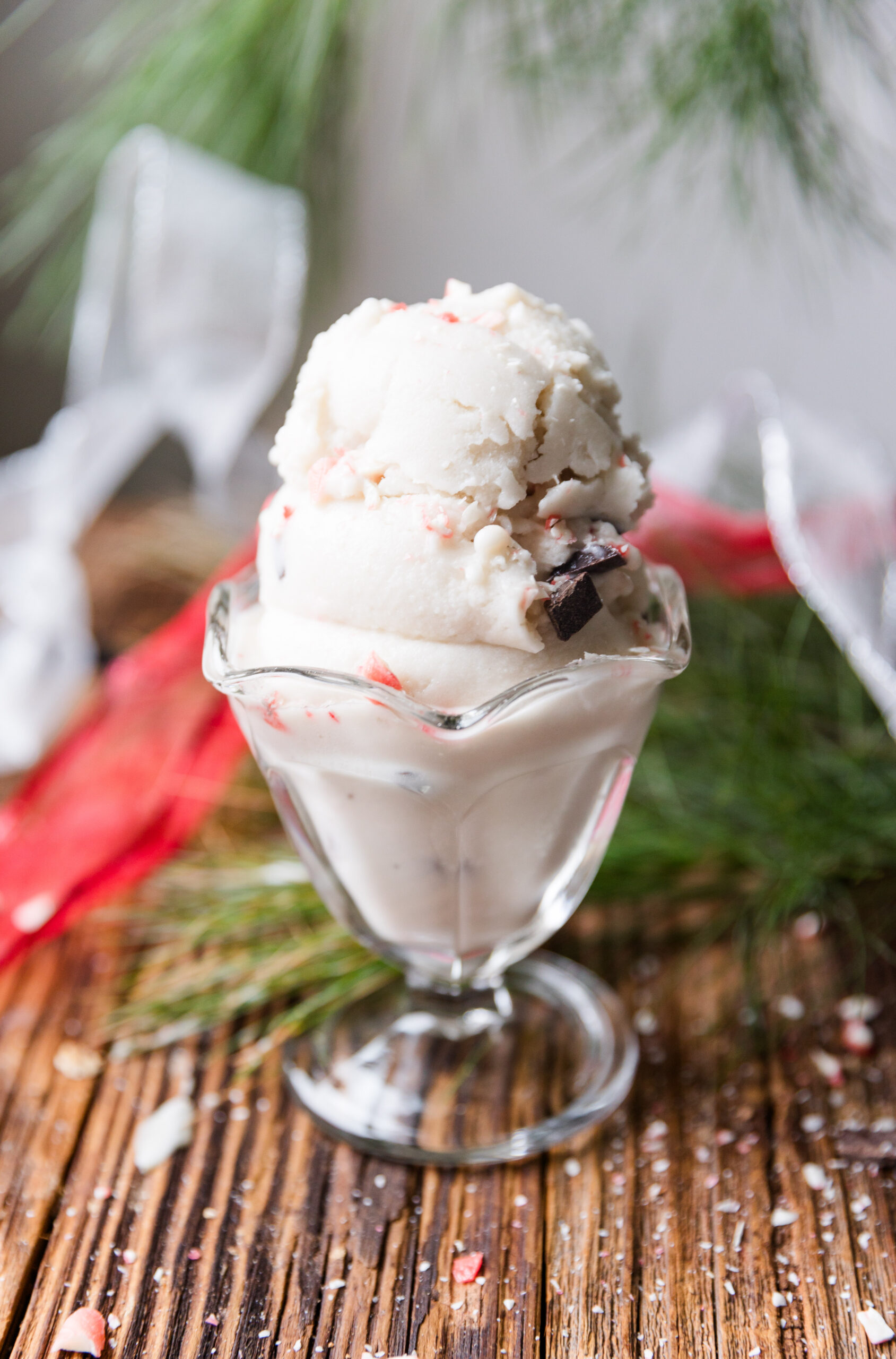 Melted peppermint candy cane ice cream with chocolate chips in a glass bowl.