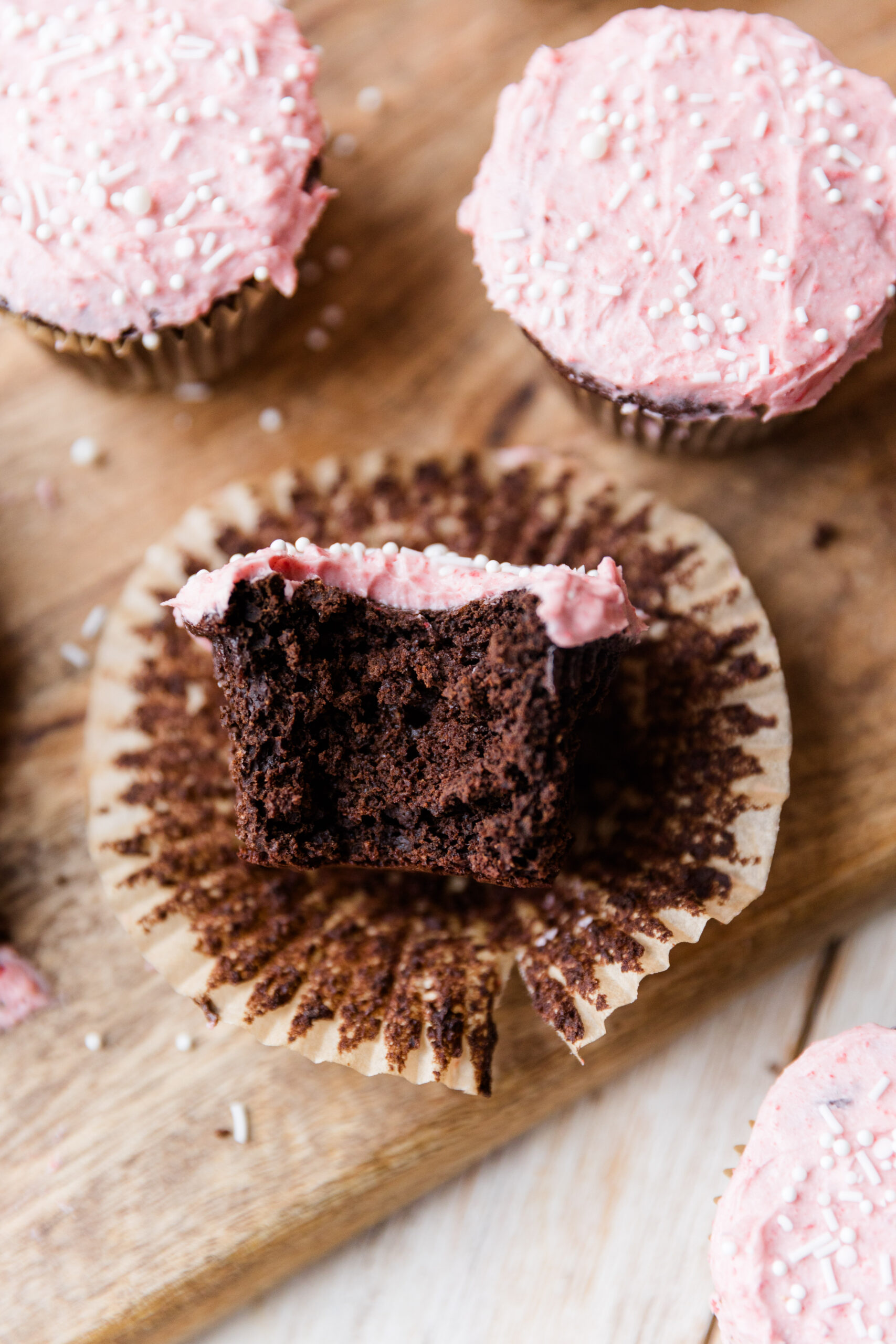 Big bite taken out of a chocolate cupcake with pink frosting.